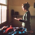 Young woman reading a letter with a baby on the&nbsp;bed